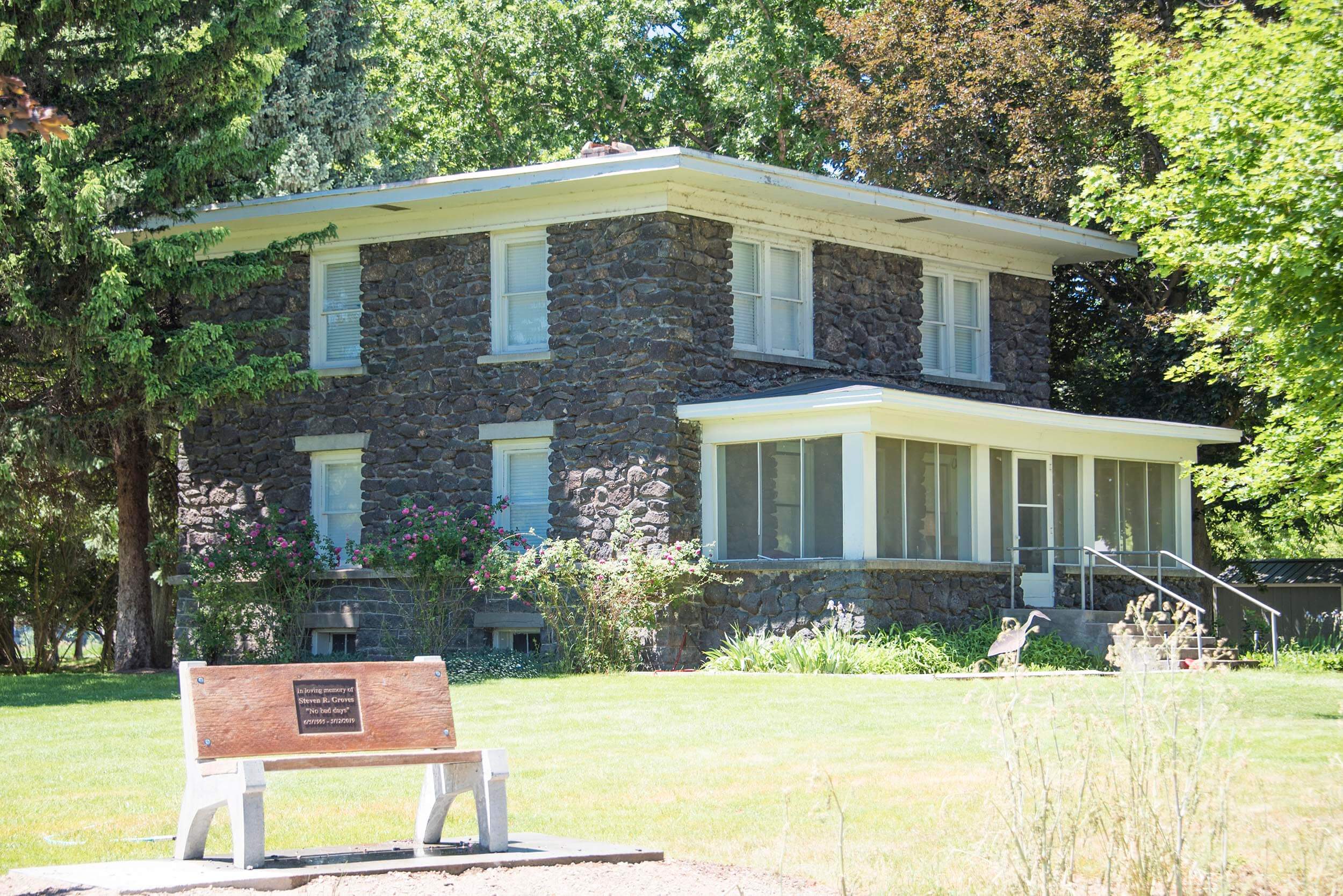 a historic building surrounded by trees with a bench in the foreground