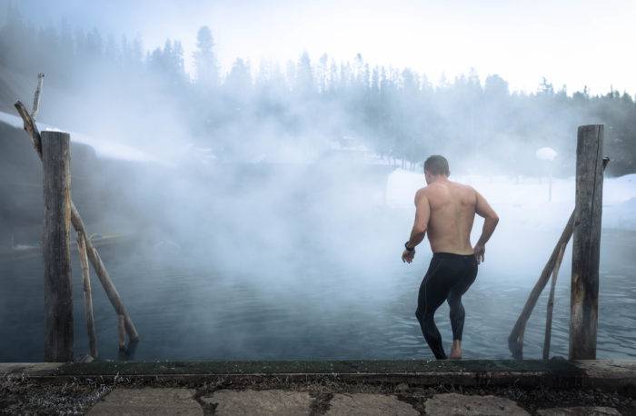 man walking down into steaming hot pool