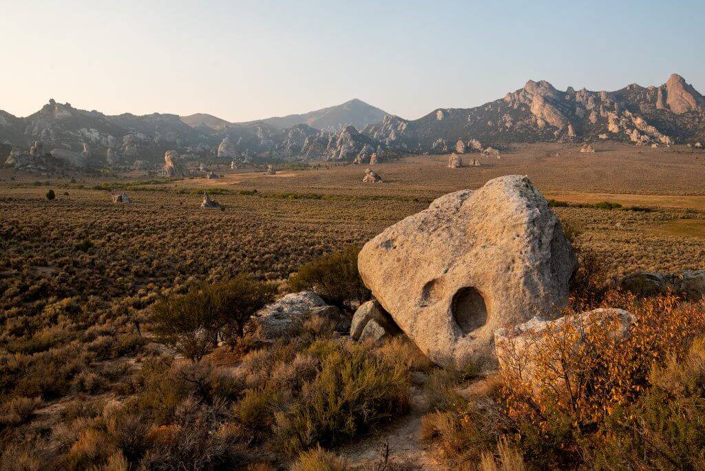 large and small boulders scattered in a field  with rock formations  in the distance