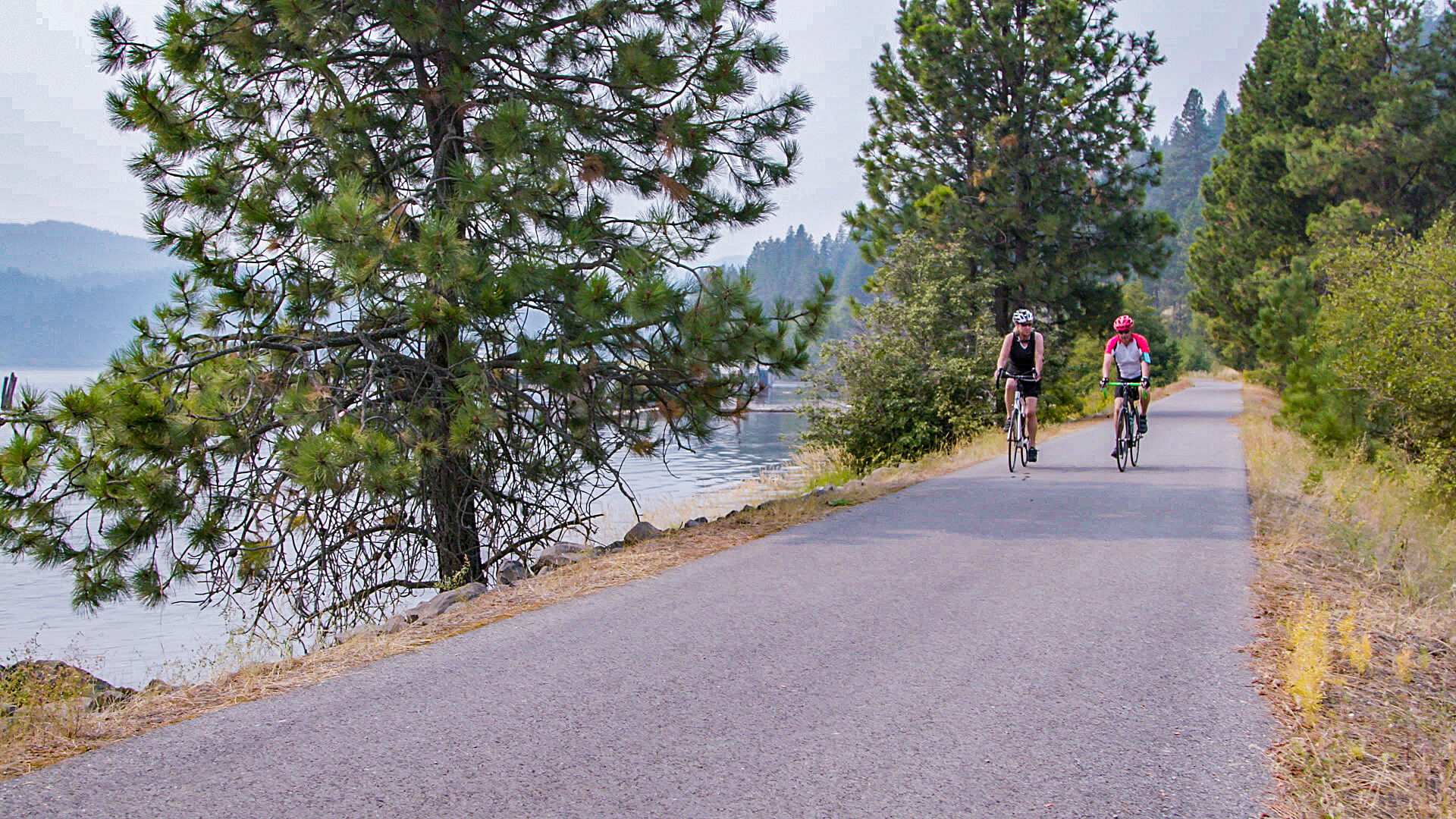 Two people riding bikes along a path at Heyburn State Park.