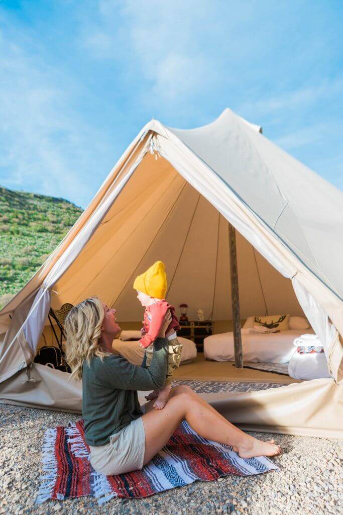 mom sitting outside glamping tent with baby