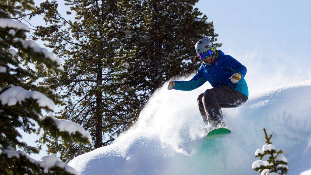 A person completing a jump on a snowboarding run at Lost Trail Ski Area.