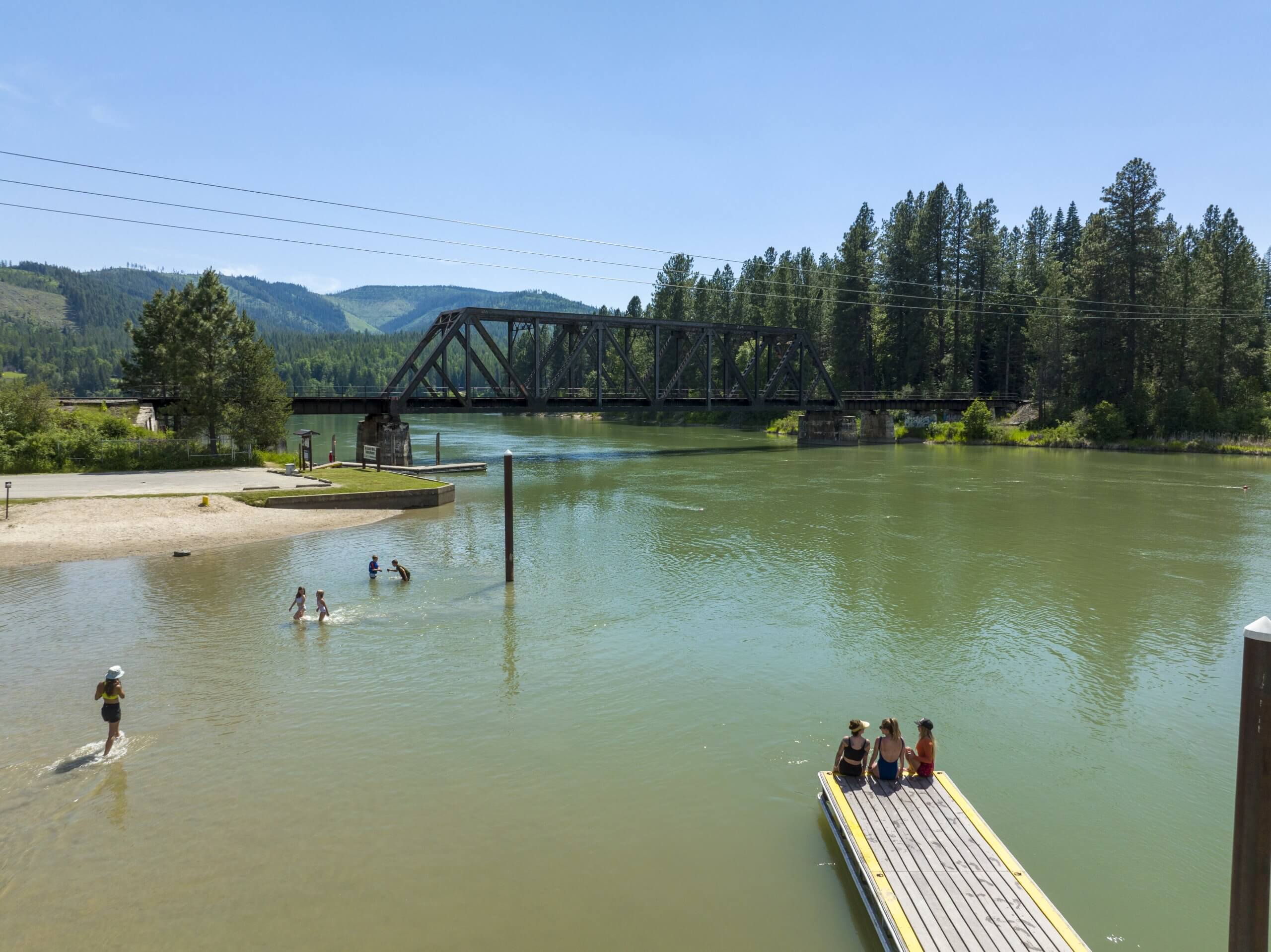 Aerial view of three women sitting on a dock overlooking Priest River.