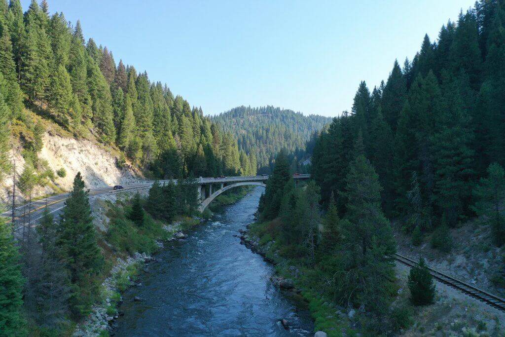 side view of a bridge crossing over a river lined with trees