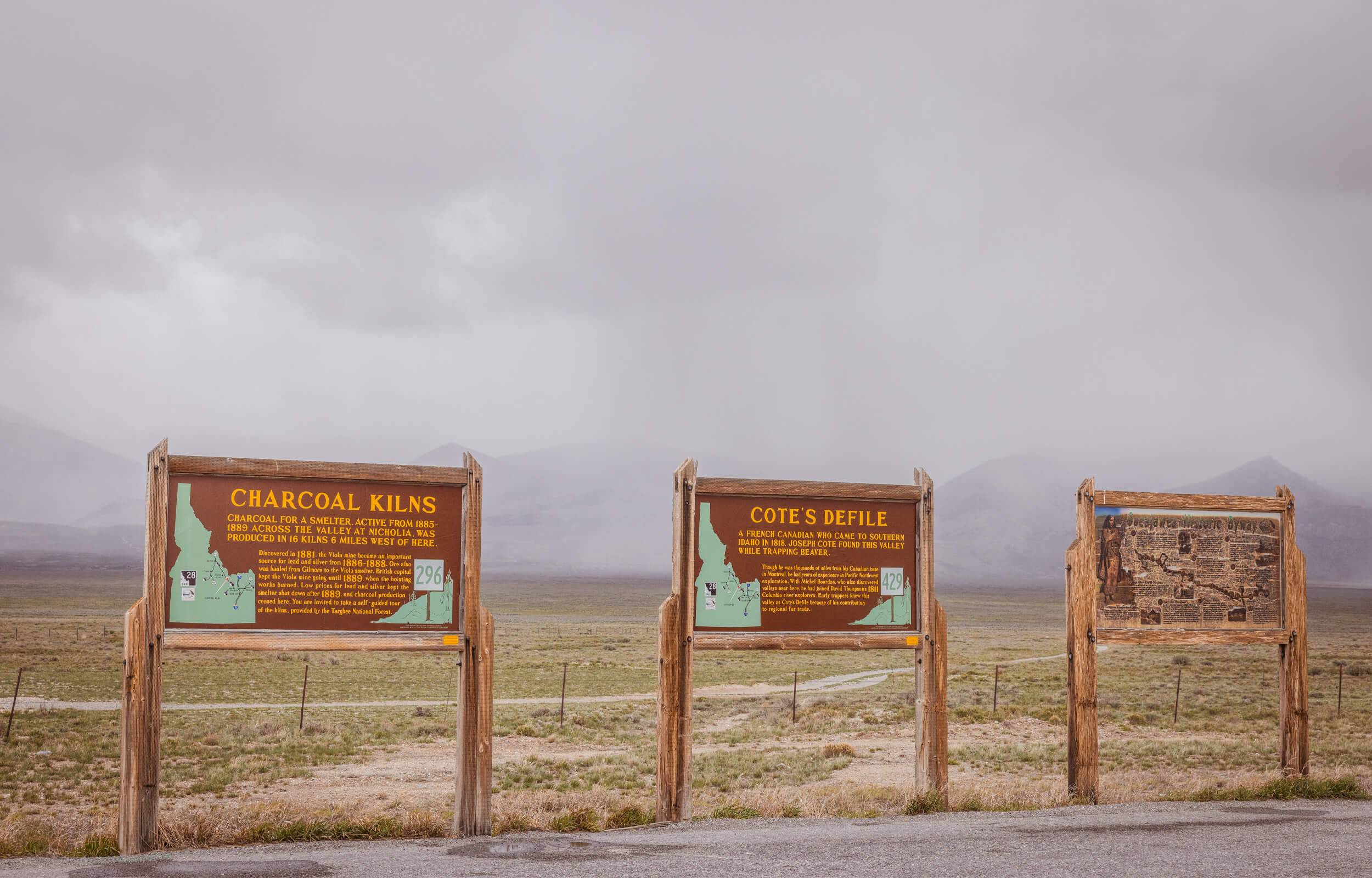 Interpretive trail signs with a wide open desert landscape in the background at Charcoal Kilns Interpretive Site.